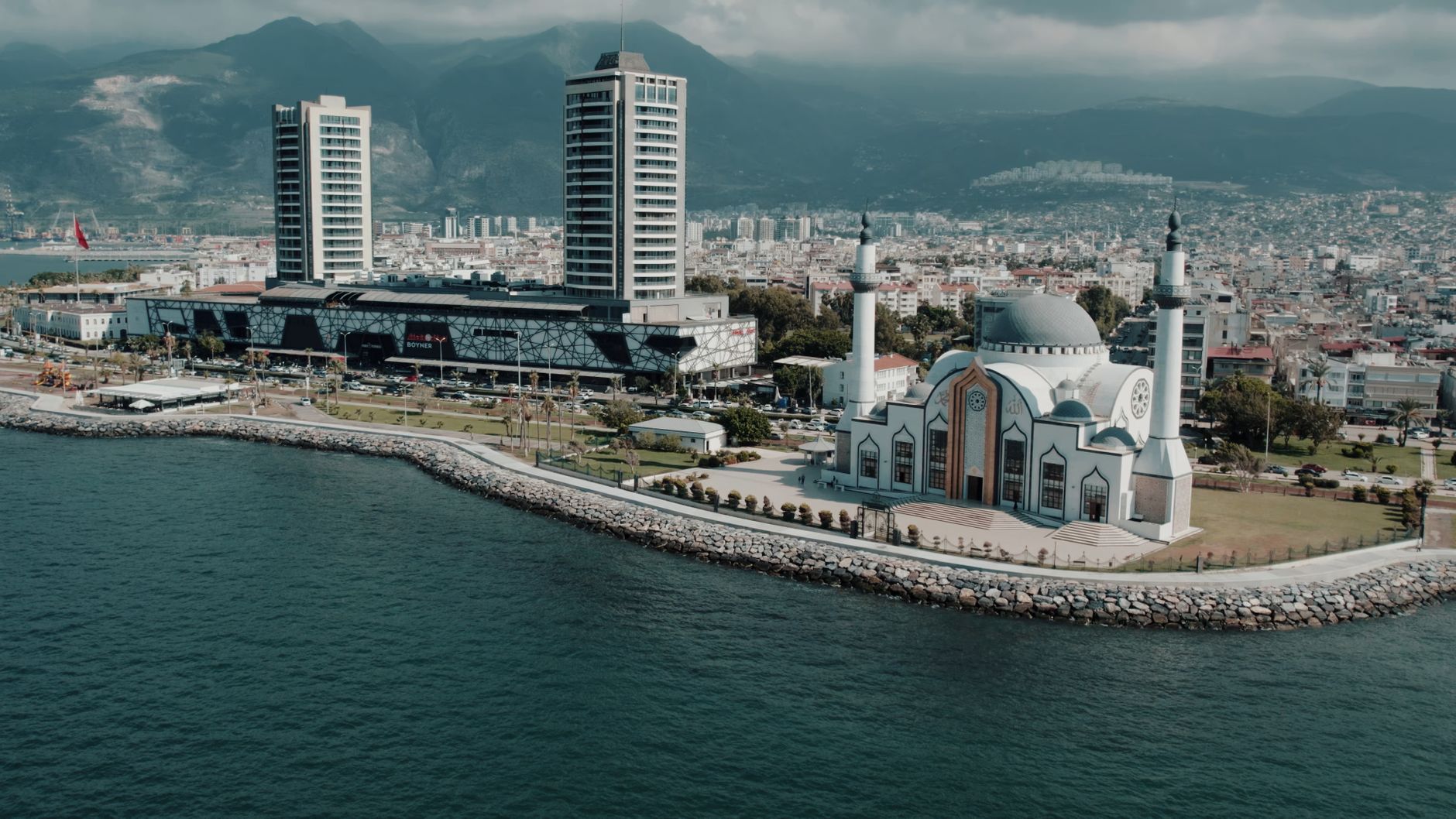 Aerial photograph showcasing İskenderun's mosque and cityscape against the mountainous backdrop on a sunny day. — 3 Biggest O