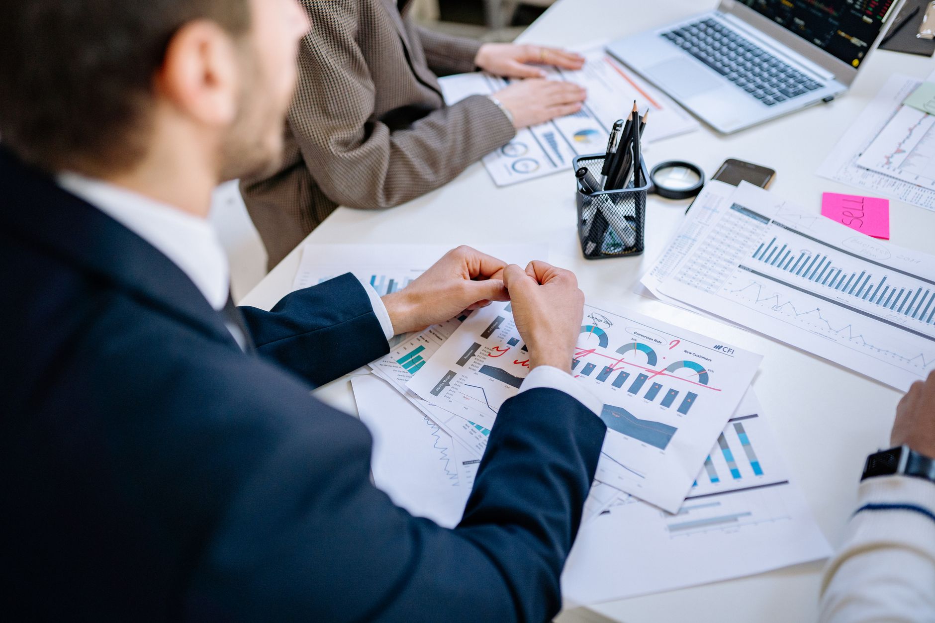 Business team analyzing financial graphs at a meeting table, fostering collaboration in an office environment. — Buy a gold b