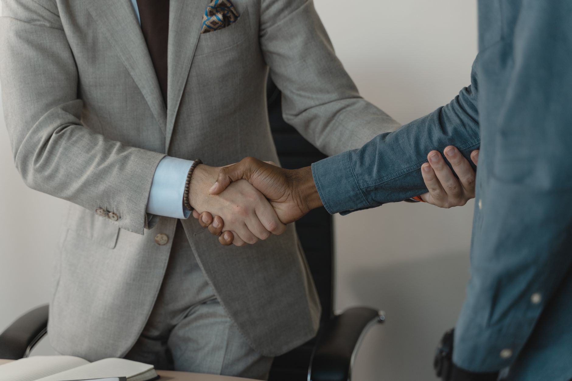 Image of a professional handshake between two businessmen in an office setting. — How Should You Sit on a Chair?