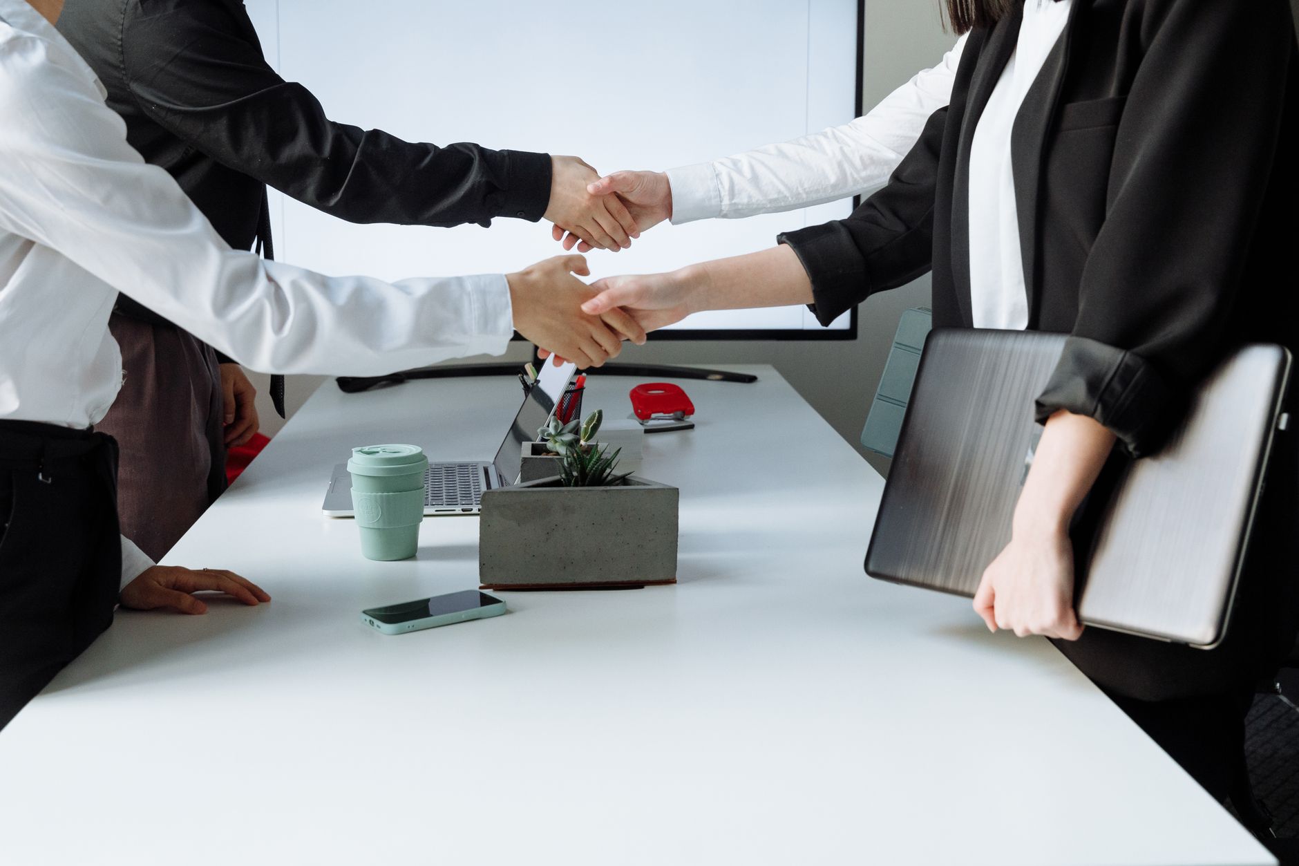 Professionals sealing a deal with a handshake across a conference table during a business meeting. — How To Get Rid Of An Unw