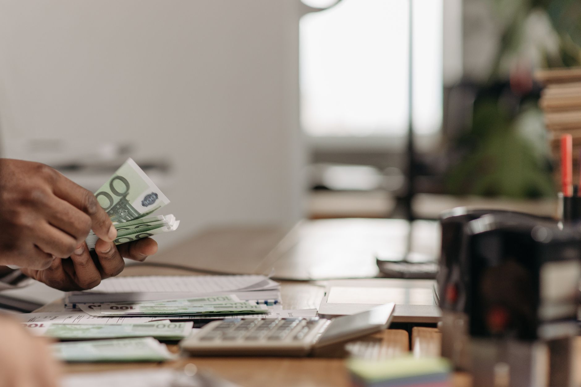 Close-up of hands counting euro bills at an office desk with a calculator. — How to make a wise decision in the investment bu