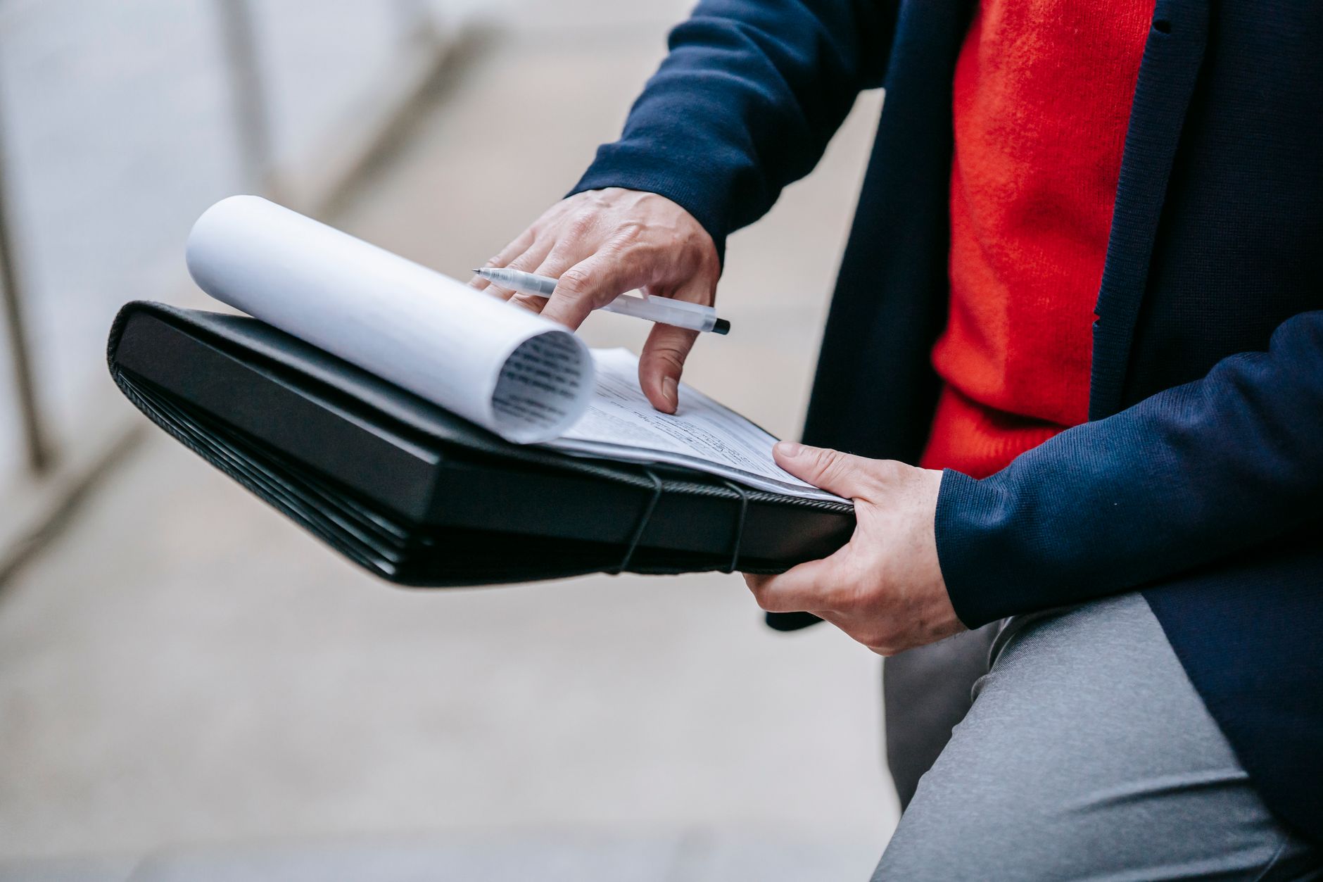 Close-up of a professional person reviewing documents outdoors. Engaged in work with focus on writing materials. — How to use