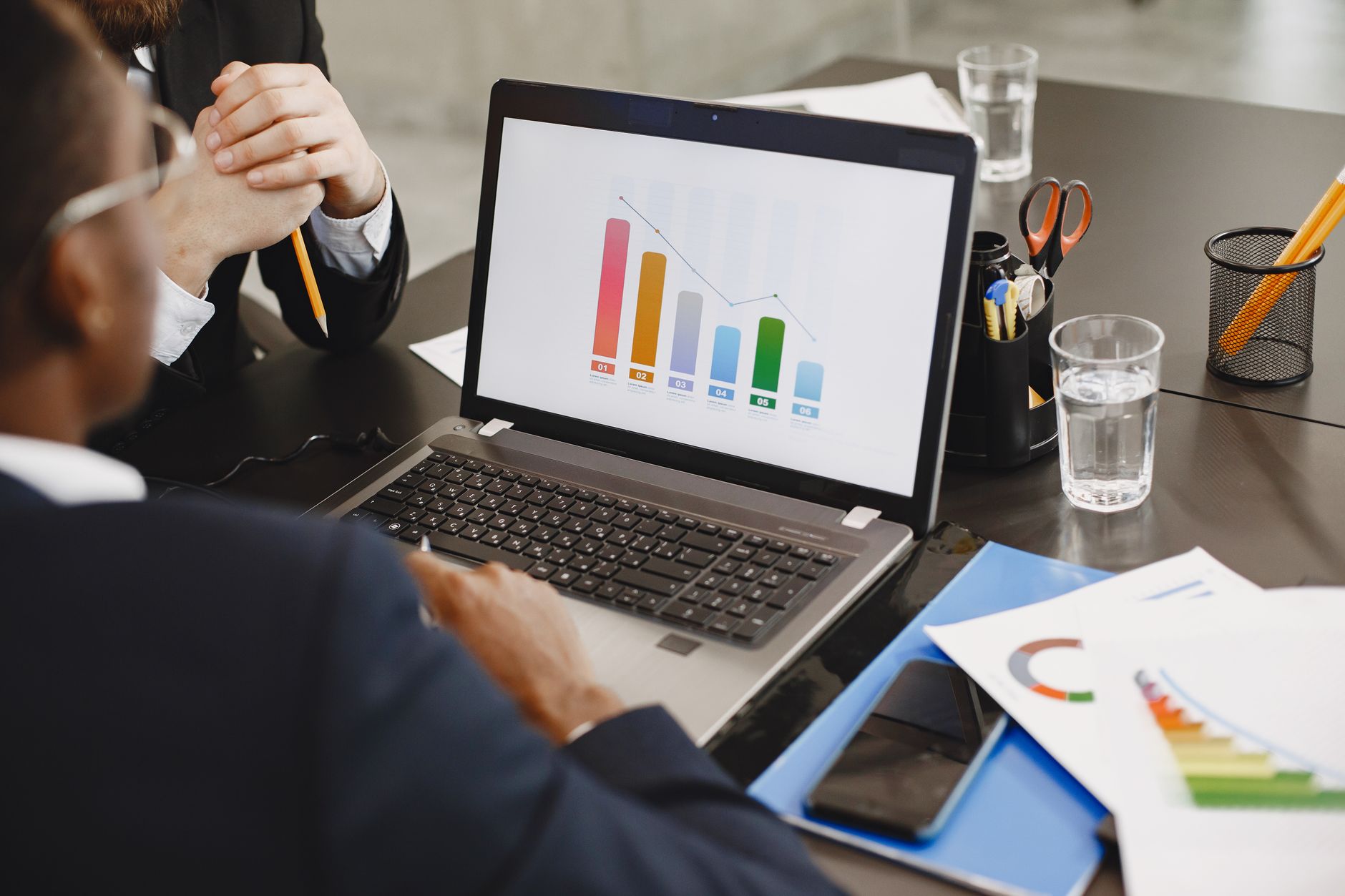 Two professionals analyzing a business graph on a laptop during a meeting. — In what ways can you, as a player, make the most