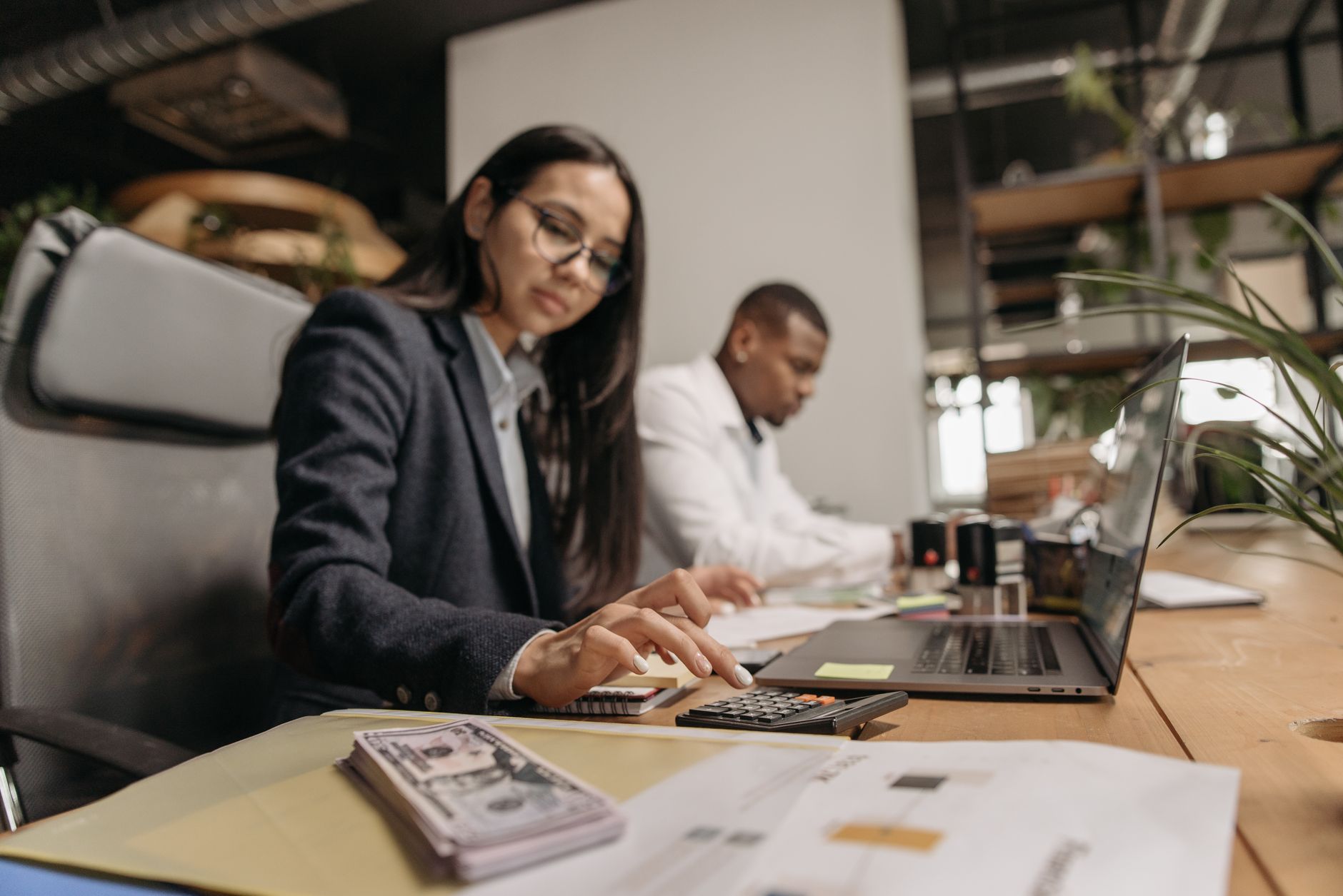 Two business professionals collaborating with a laptop and calculator in a modern office. — Insurance for Mobile Mechanics: F