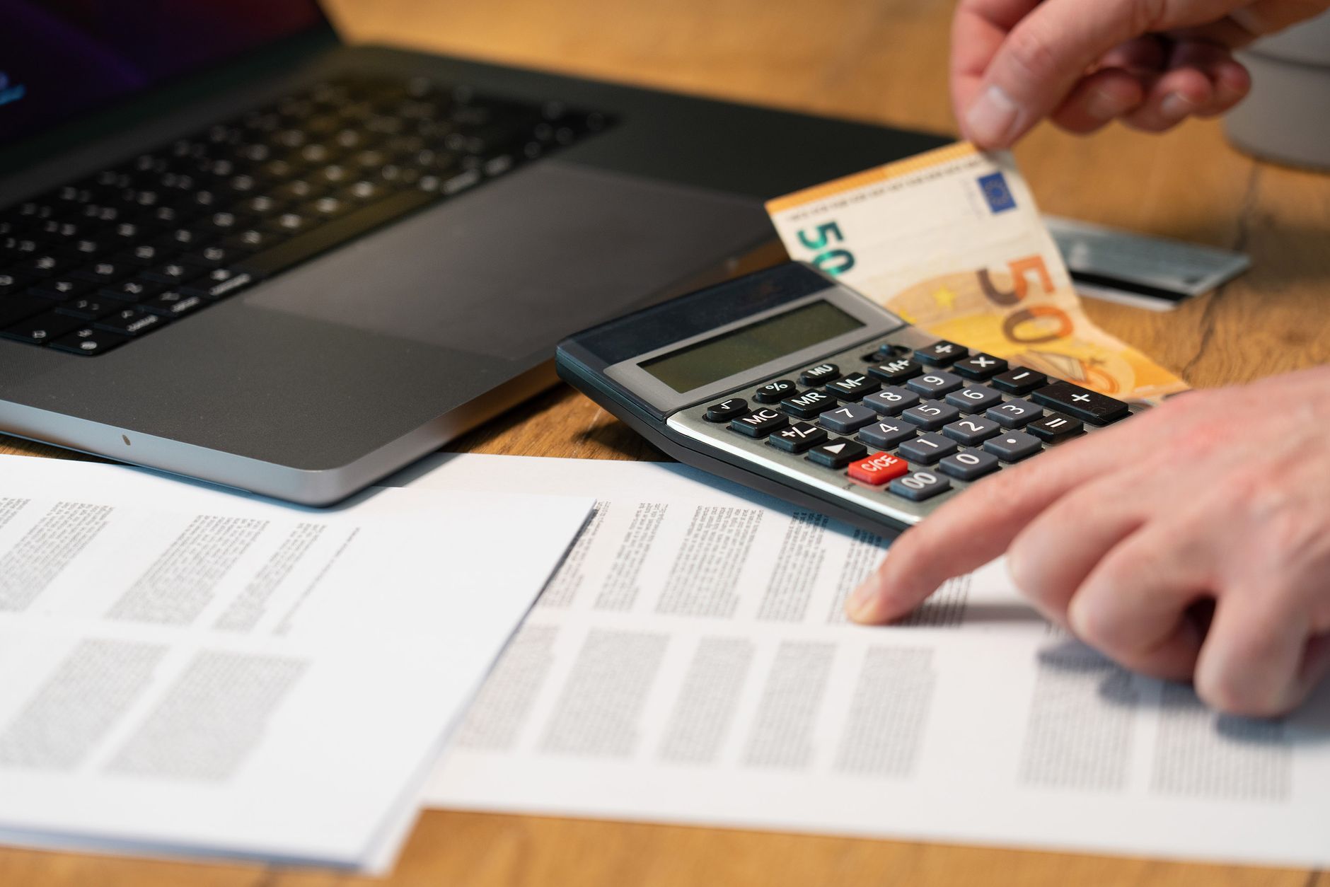 Close-up of hands using calculator with euro notes and laptop on desk. — Learning more about the crypto trading process