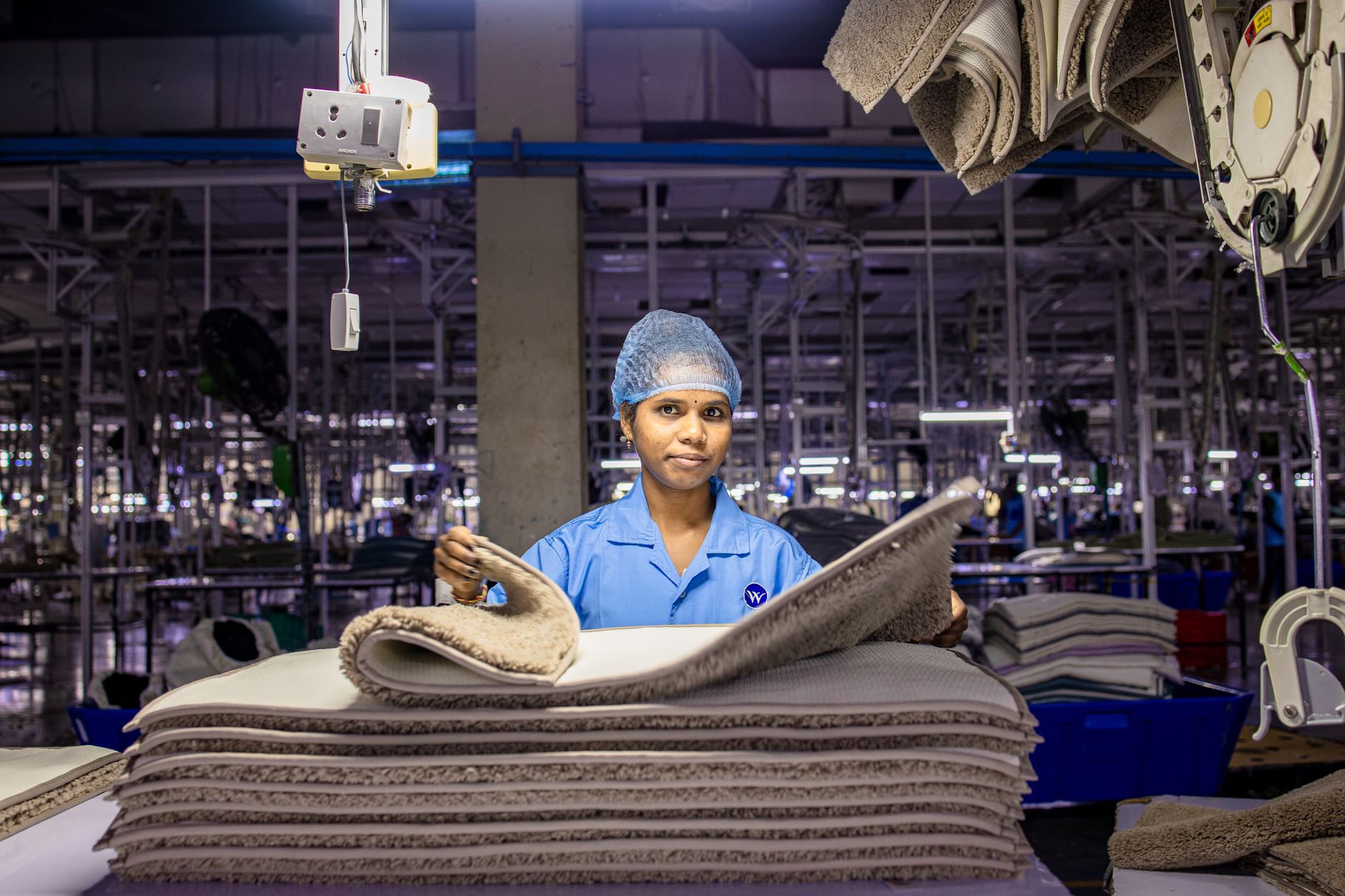 A female worker arranges fabrics in a busy textile factory interior. — Myths About Employed In The IT Industry