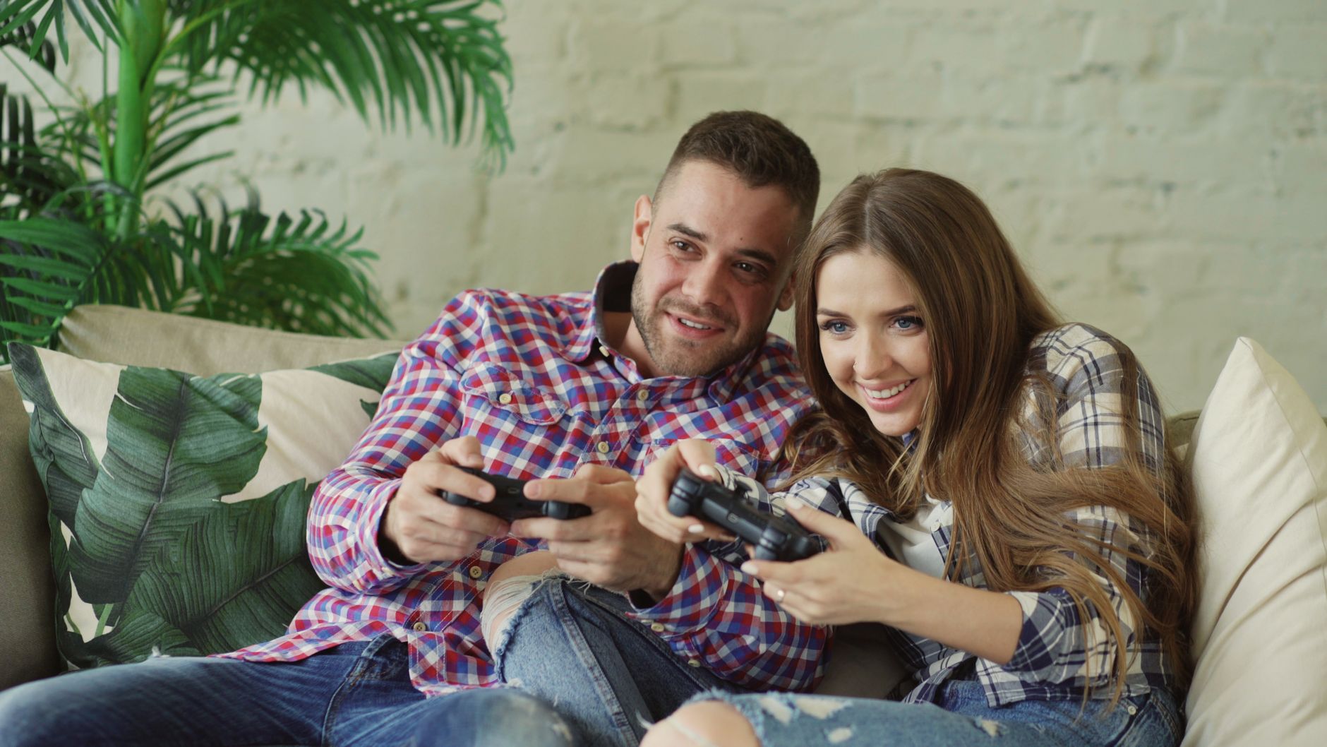 Happy couple enjoying video games together at home on a cozy sofa. — No Deposit USA Casinos Offering Bonuses Without Initial