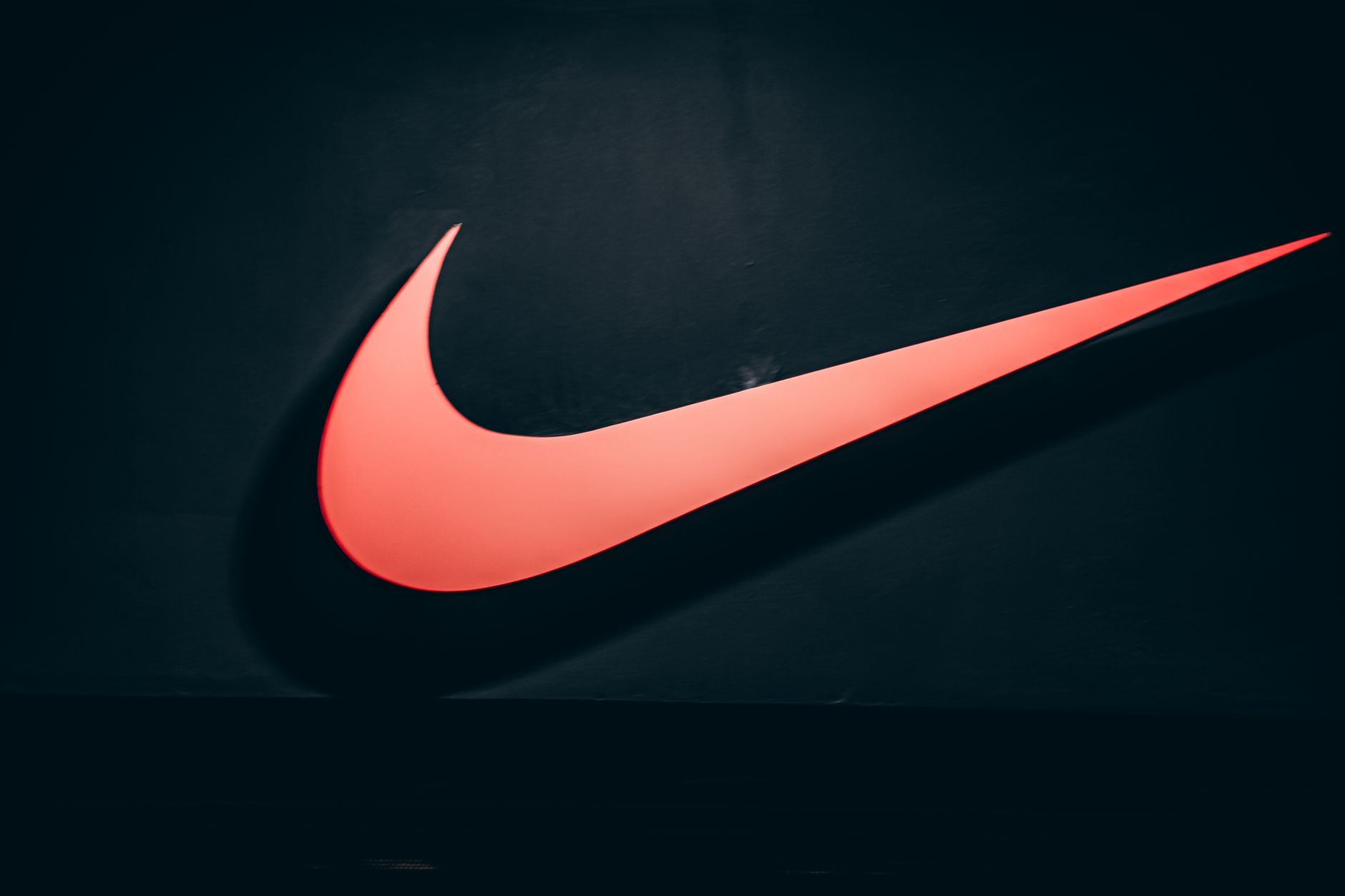 Vibrant red Nike swoosh logo displayed on a dark, minimalist backdrop symbolizing sports and lifestyle. — Produce a Champion