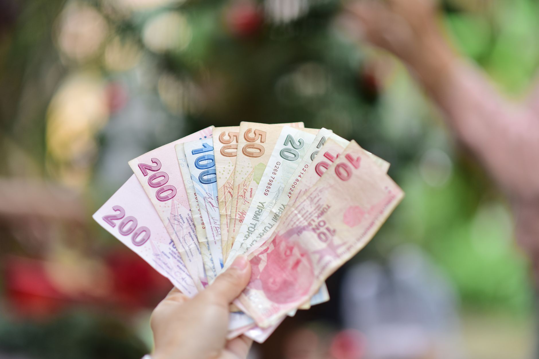A hand holding multiple Turkish Lira banknotes in an outdoor setting, showcasing various denominations. — Simple Ways To Buil