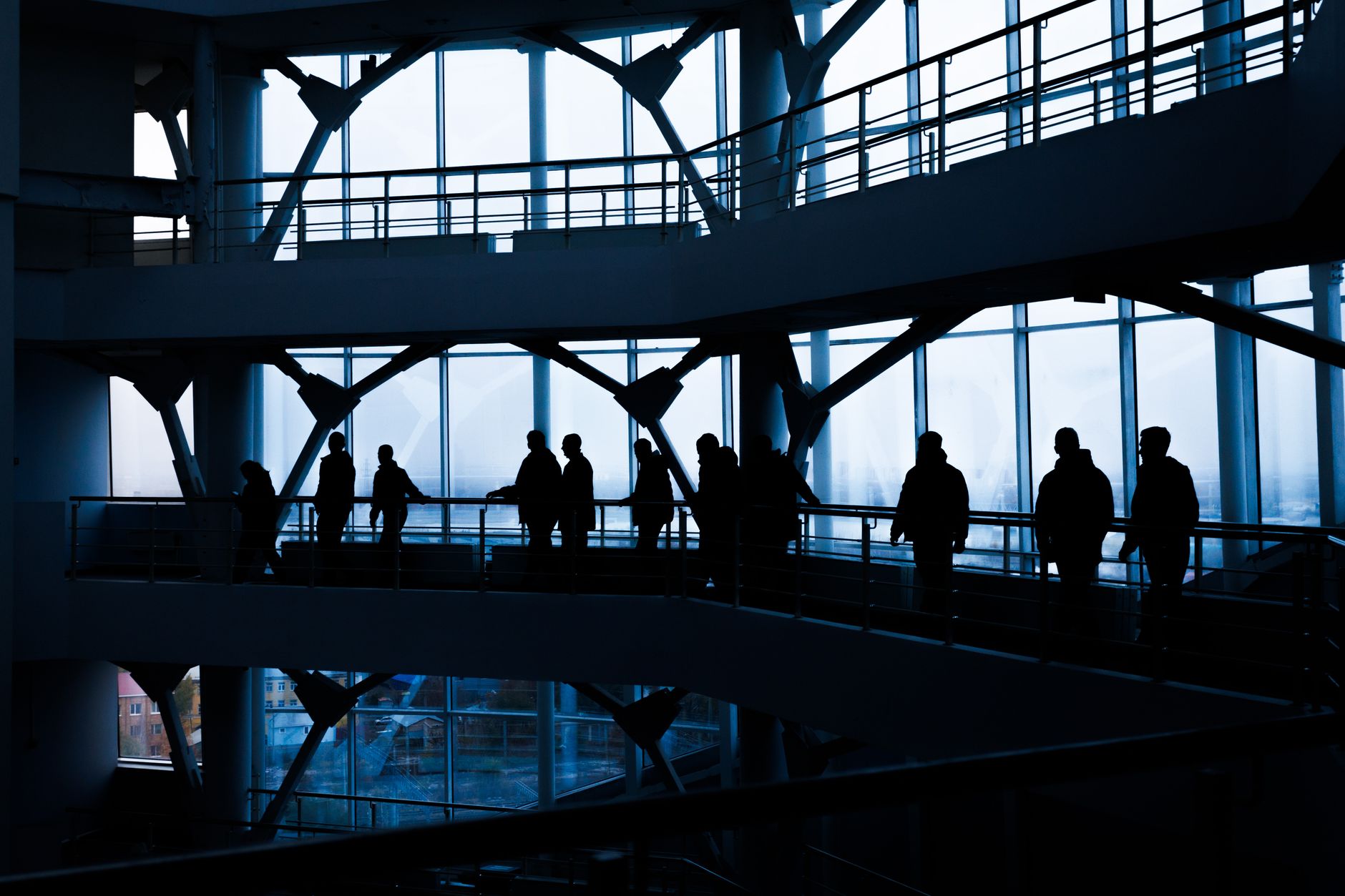 Silhouettes of people walking in a modern architectural building with large windows. — Influence Marketing Trends in