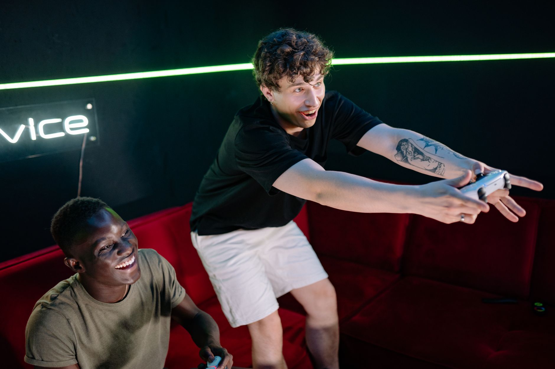 Two young men having fun playing video games in a cozy indoor setting. — Online Casino NZ: Examining the Impact on th