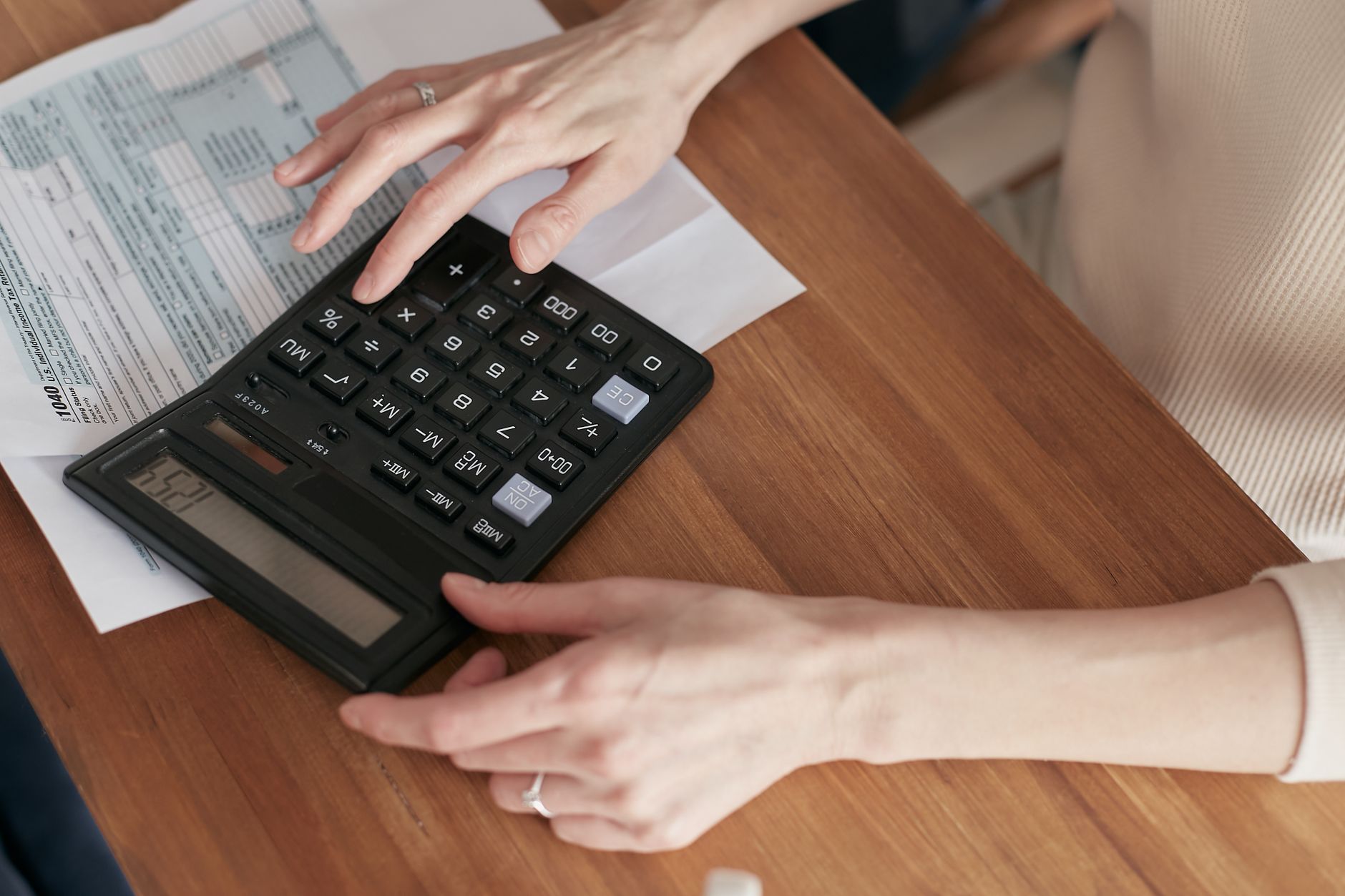 Close-up of a woman using a calculator and reviewing bills at home. — Successful Online Trading through Cardano DEX Exchange