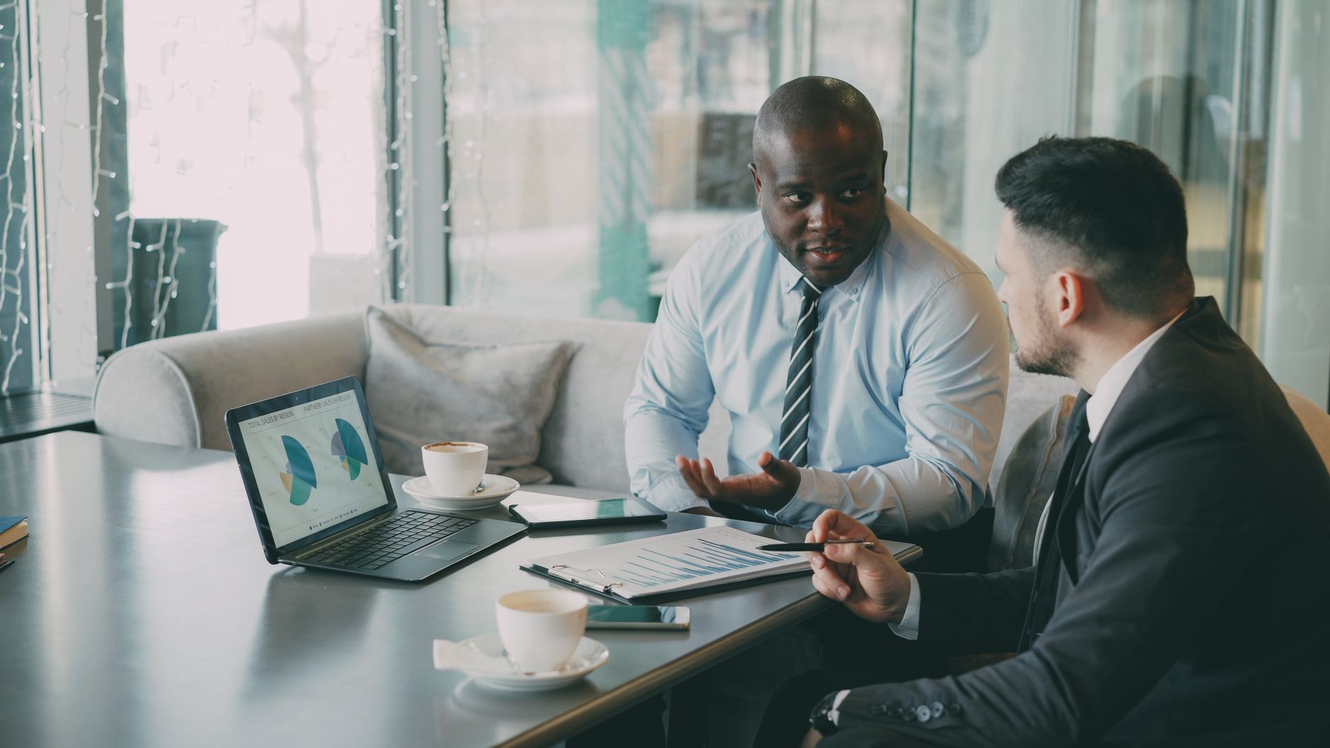 Two business professionals engaged in discussion over laptops and documents. — "The Joy of Bringing People Together: Emotiona