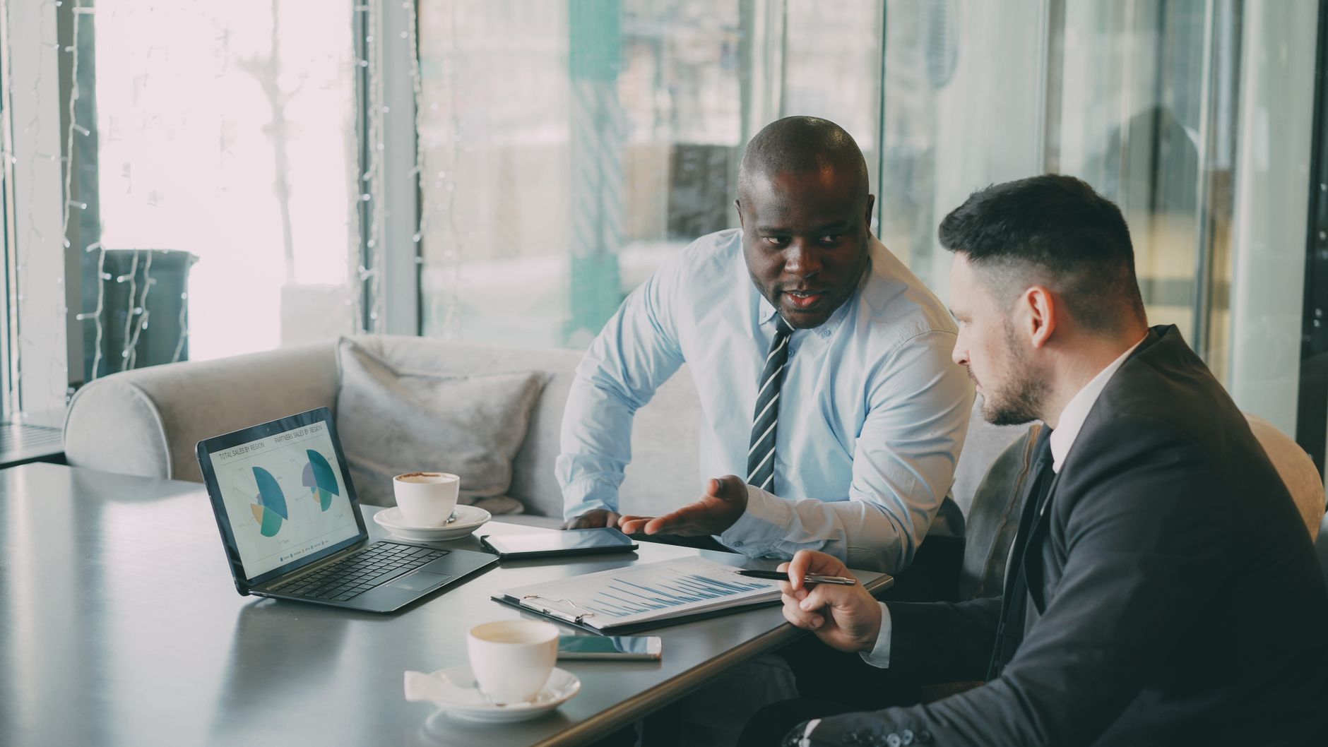 Two businessmen discussing data at a cafe while enjoying coffee. — Ways The Find The Right Real Estate Agent- 3saestate